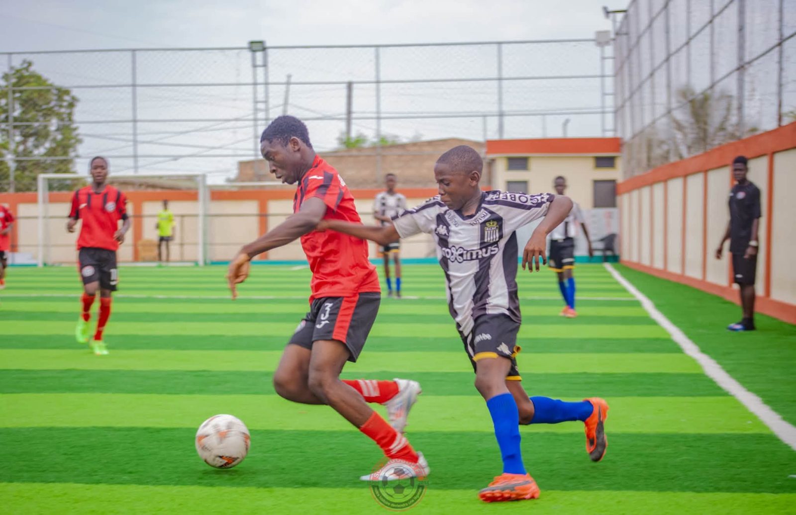 Un joueur de Solingobou FC, en rouge et noir, conduit le ballon