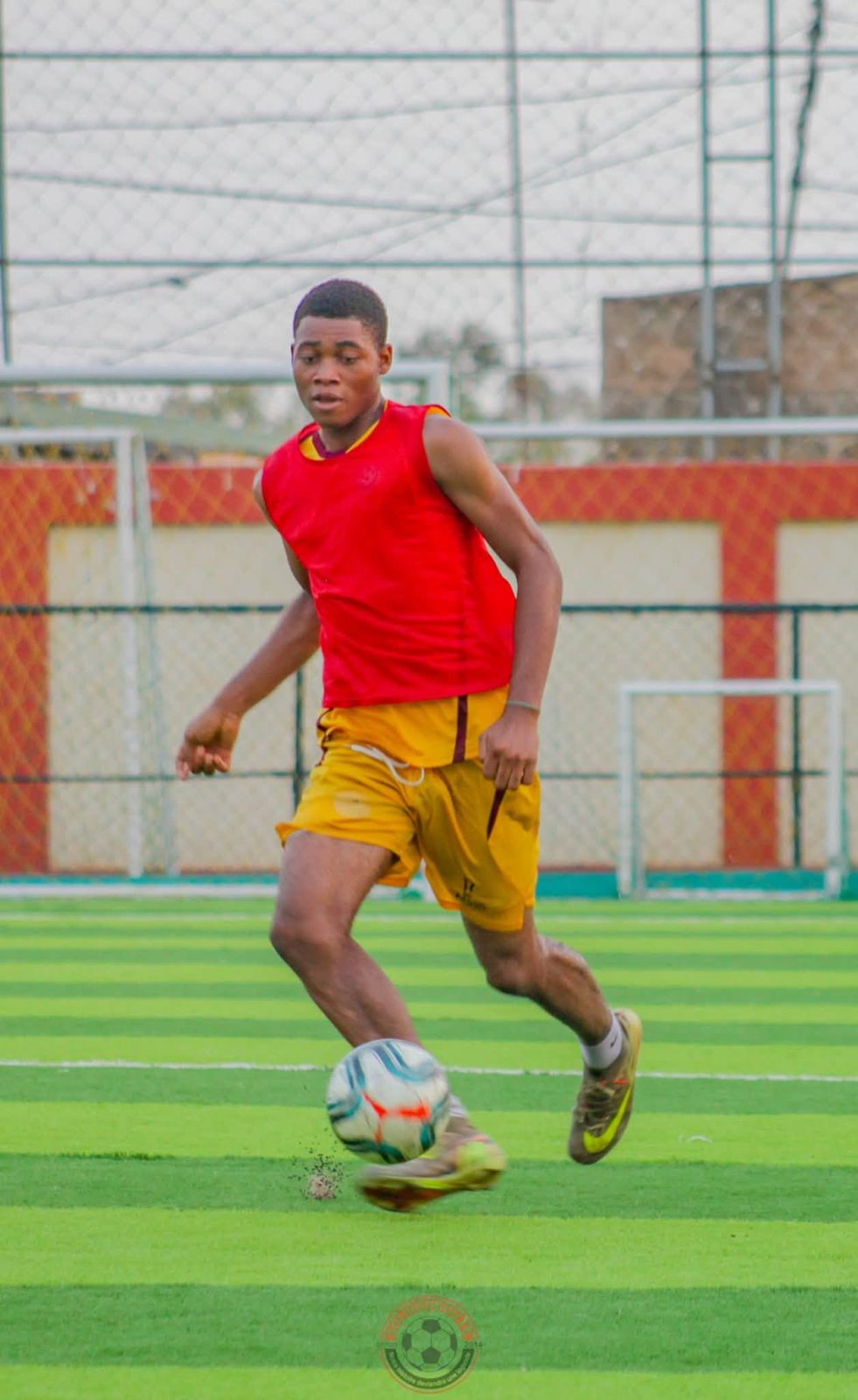 Un joueur en chasuble rouge conduit le ballon