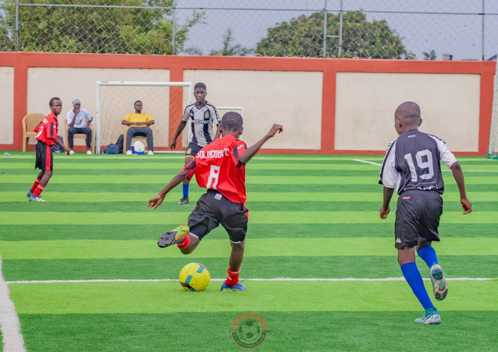 Un joueur de Solingobou FC, en rouge et noir, frappe le ballon
