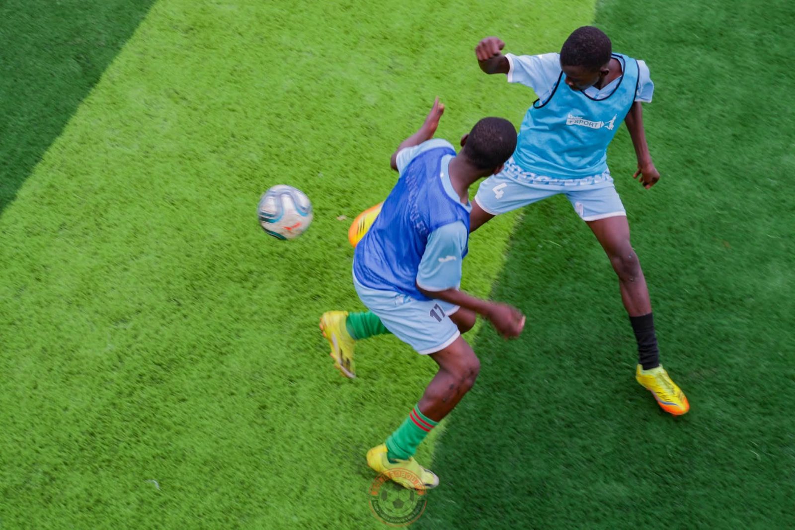 Deux jeunes joueurs se disputent le ballon, vus d’en haut